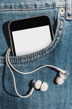 Kulaklıklı kot pantolonun cebinde boş model ekran cep telefonu.