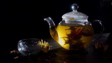 bir mavi arka plan, natrmort çay ve çiçeklerle, bir fincan içine dökülür çay çaydanlık