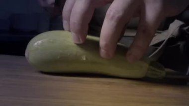 Ahşap mutfak tahtasındaki bir şef tarafından bıçakla kabak dilimlemek, aşçının elleri.
