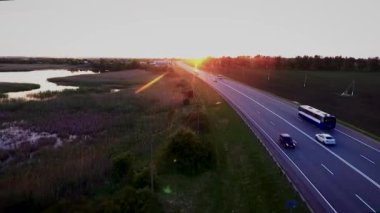Karayolu trafik arabalar karayolu üzerinde. Yeşil buğday alanları bir yükseklikten Rusya Federasyonu Krasnodar asfalt yol gün batımında. Quadrocopter ile çekim.
