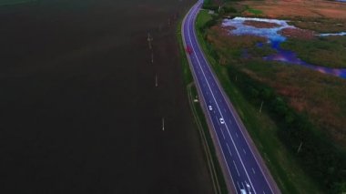 Vespers karayolu, karayolu üzerinde araçların hareketi. Kırmızı kamyon hareket. Rusya, Krasnodar asfalt yol. Hava görünümü Lotus Gölü. Quadrocopter ile çekim.