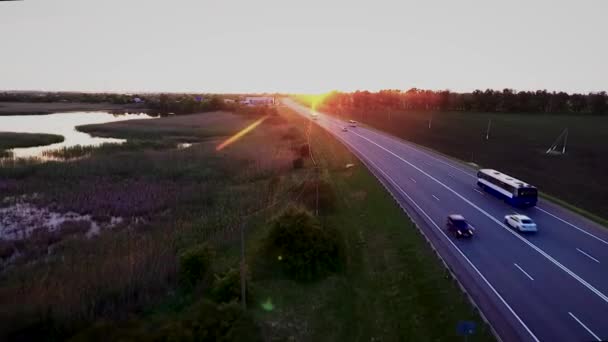 高速道路高速道路交通車。夕暮れ時、ロシアのクラスノダール地方の舗装道路の高さから緑の麦畑。Quadrocopter で撮影. — ストック動画