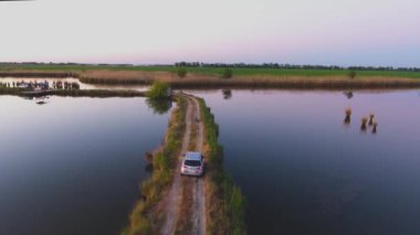 Hava fotoğrafçılığı. Arabayı göller arasında dar bir yol hareket eder. Balık pond. Yaz sabahı. Ivanovskaya. Krasnodar. Rusya.