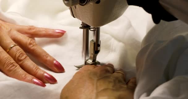 Mãos das mulheres costurando tecido branco na máquina de costura . — Vídeo de Stock