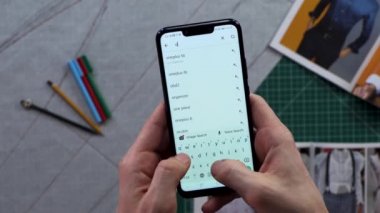 Mens Close-Up holding akıllı telefon içinde belgili tanımlık geçmiş'deki dikey yeşil ekran eller. Giyim satın alma. Çevrimiçi mağaza arama. Online alışveriş. Seçim dikiş makinesi.