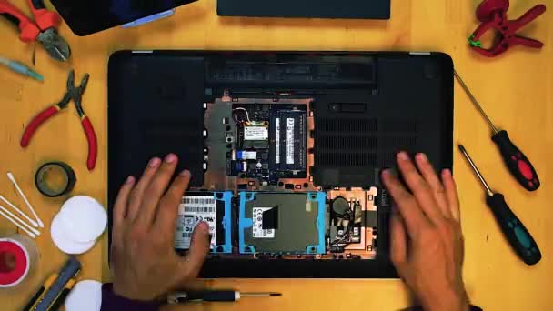 Vista superior do engenheiro técnico reparando laptop em sua mesa cercada por suprimentos e equipamentos — Vídeo de Stock