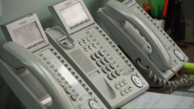 El telefonu alır ve telefonda bir numara çevirir.