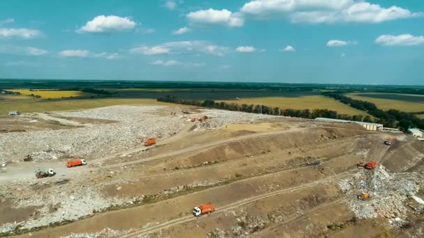 Wysypisko śmieci na tle zielonych pól. Sprzęt do utylizacji śmieci trafia na wysypisko drogowe. Seagull krążą. Ogromny widok garbage dump z drona. — Wideo stockowe