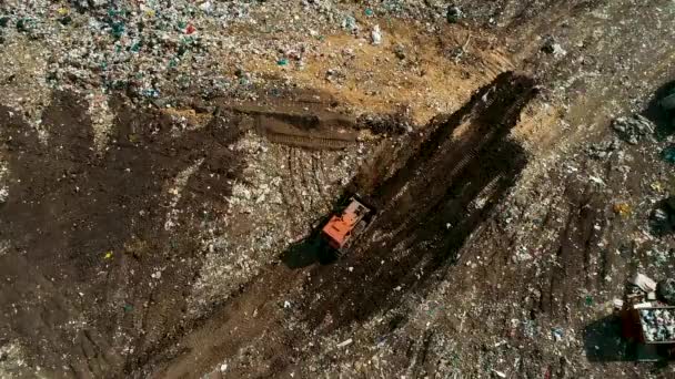 Bulldozer In una discarica aperta di rifiuti solidi, Raccoglie un mucchio di spazzatura . — Video Stock