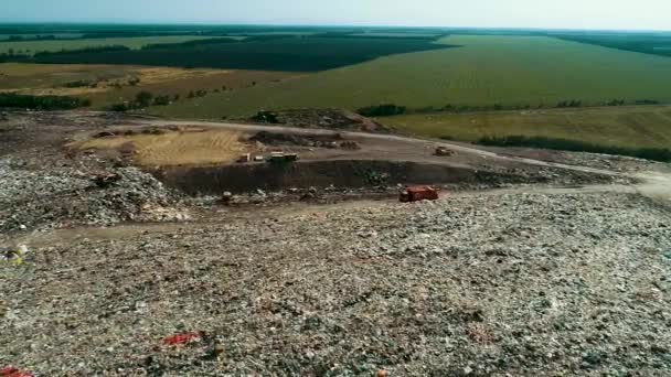 Big orange garbage truck moving among the wreckage. landfill. — Stock Video