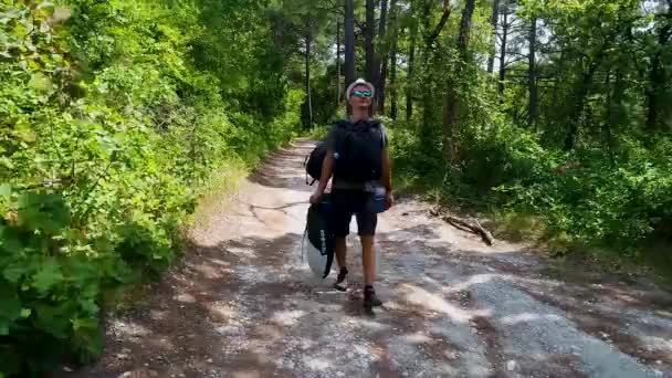 Um jovem turista em uma trilha florestal vai com uma mochila em uma floresta de pinheiros. Dzhankhot região de Krasnodar agosto 2019 — Vídeo de Stock