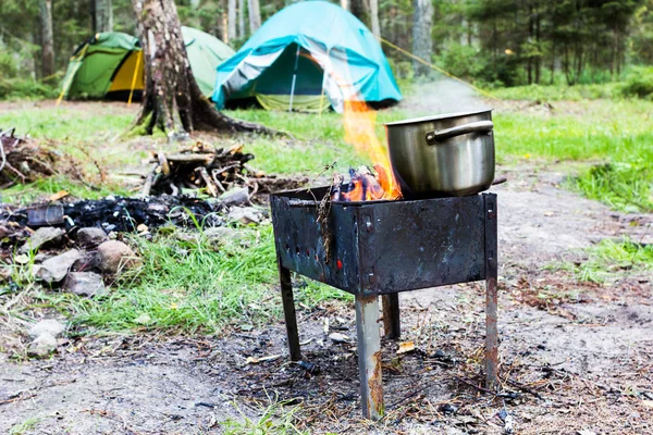 Preparing food on campfire. Summer camping in the forest.
