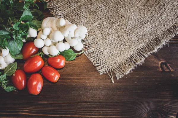 Plant-based food background. Copy space for text. Fresh tomatoes, shimeji mushrooms and basil on wooden board. Healthy food.