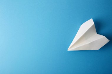 Düz beyaz kağıt uçak ve boş kağıt pastel mavi renk arka plan üzerinde yatıyordu. Yatay.
