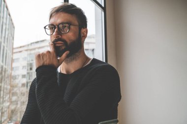 Giyen moda gözlük ile lots-in kopya alanı bulanık arka plan üzerinde panoramik pencerelere karşı genç yakışıklı adam.