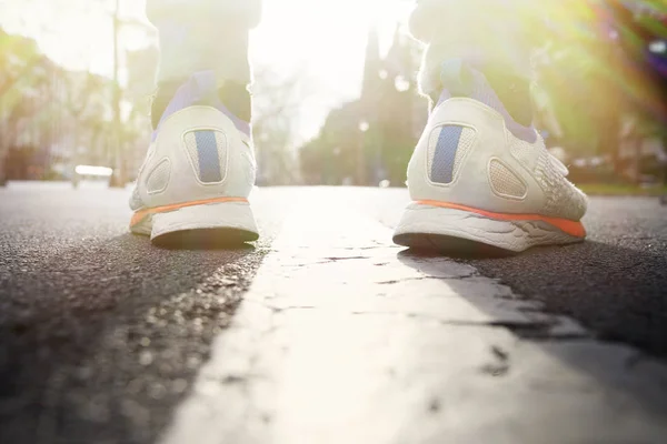 Pies de corredor corriendo en la carretera primer plano en zapato. Hombre fitness urbano sunrise jog entrenamiento concepto de solidez. Fondo borroso . —  Fotos de Stock