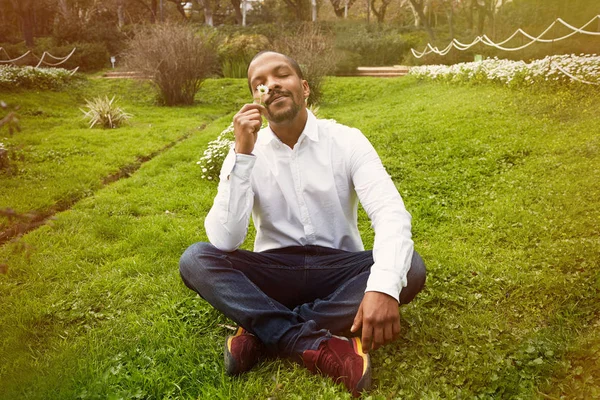 Молодой американский бизнесмен в неформальной одежде медитирует в позе лотоса, делая глубокий вдох на зеленых лугах. . — стоковое фото