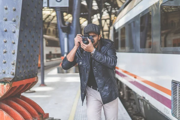 Hombre atractivo fotógrafo turístico haciendo foto en la cámara de cine hipster vintage analógico en la estación de tren.Concepto ideas de viaje y estilo de vida libertad . — Foto de Stock