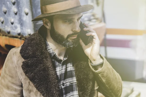 Hombre barbudo en sombrero hablando en un teléfono móvil.Retrato al aire libre del hombre moderno con teléfono inteligente móvil afuera en la plataforma del tren esperando el tren . — Foto de Stock