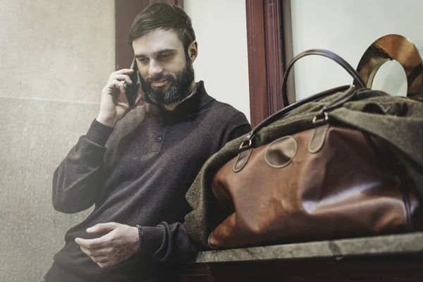 Empresario profesional casual llamando a través de teléfono inteligente en la estación de tren. hombre barbudo en hablar en un teléfono móvil . — Foto de Stock