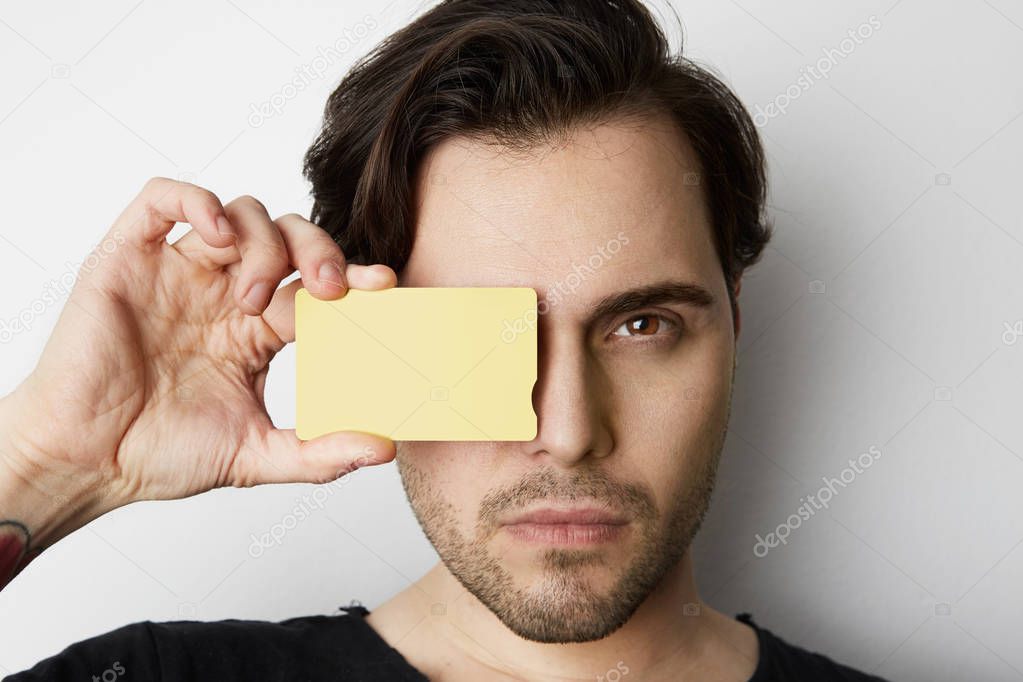 Young man holding empty yellow color credit card front of male face on blank white background. Business mock-up background for message writing. Horizontal Mockup
