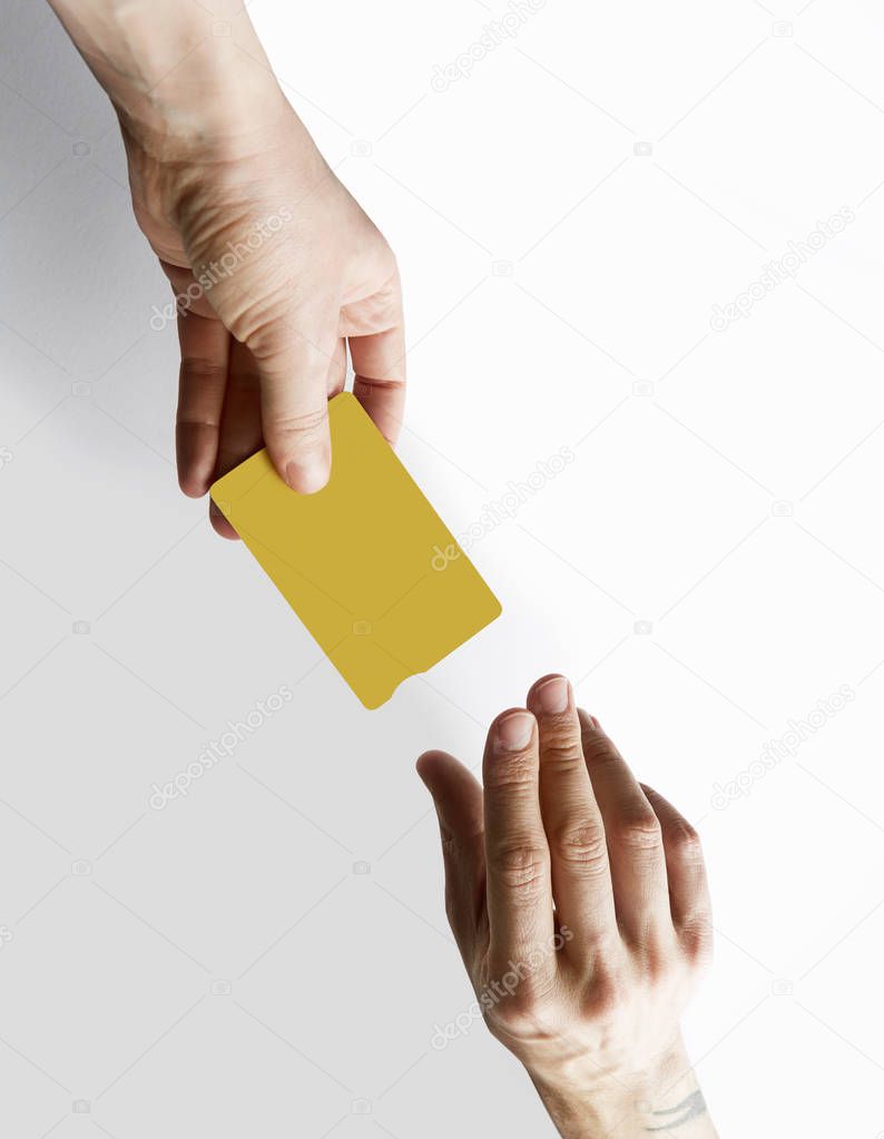 Mockup of yellow color credit card give male hands on empty white desk background. Business mock-up background for message writing.Top view. Vertical.