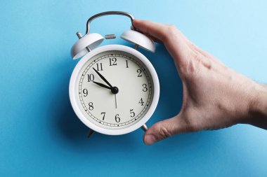 Boş mavi renk arka plan üzerinde beyaz vintage çalar saat