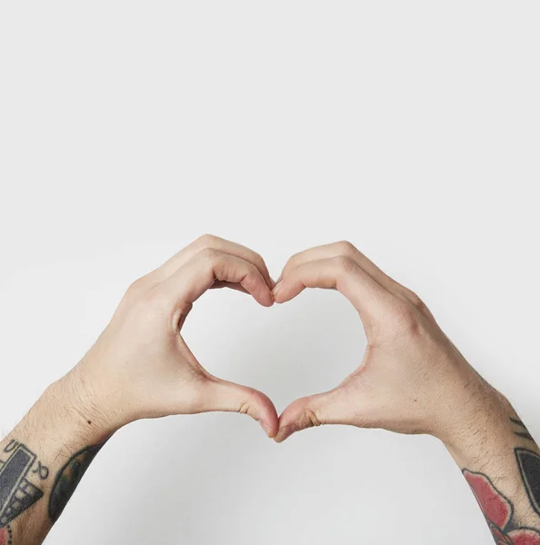 Mani maschili del tatuaggio che modellano un simbolo del cuore su sfondo bianco . — Foto Stock