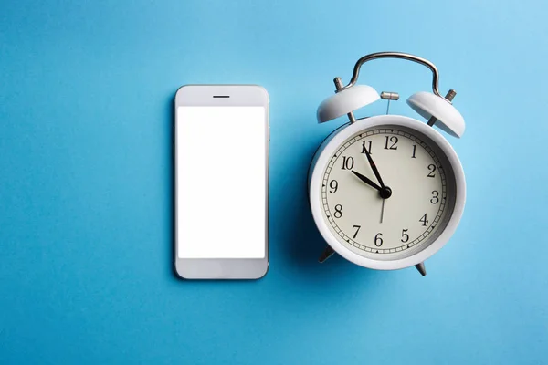 Fehér vintage ébresztőóra és mozgatható telefon-val üres képernyő, üres kék szín háttér — Stock Fotó
