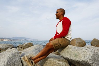 Gülümseyen genç Afro-Amerikan hipster enjoing yaz günü şehir dışında sahilde.