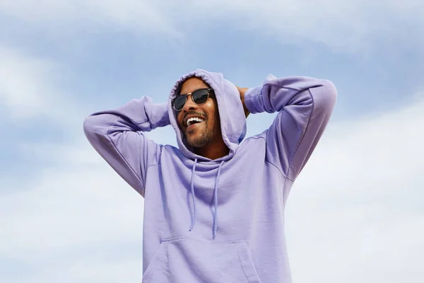 Sommaren active sports koncept. Leende glada unga afroamerikansk man hipster i sport hoody och solglasögon på stranden. — Stockfoto