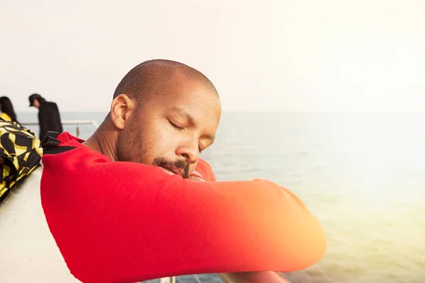 Csinos fiatal afro-amerikai csípő ember, pihentető a strandon, csukott szemmel. Vértes portré Stock Kép