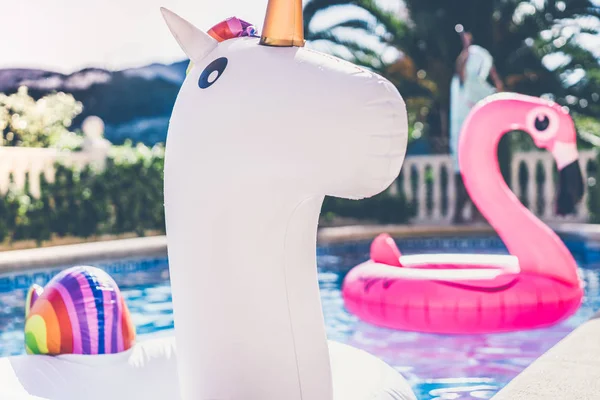 Надувний барвистий білий єдиноріг і рожевий фламінго в басейні. Час відпустки у басейні з пластиковими іграшками. Релаксація і весела концепція . — стокове фото