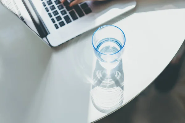 Werkende momenten thuis. Jonge vrouw te typen op laptopcomputer zittend aan de houten tafel in licht gekleurd woonkamer van moderne huis. — Stockfoto