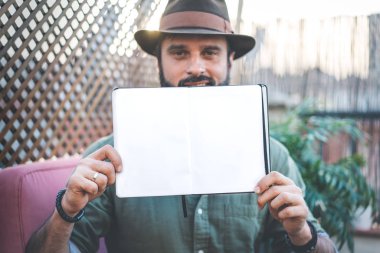 Not defteri açık boş çarşafları ile üzerinde kafe terasında vakit sırasında elele çekici Hipster blogger. Kopyala Yapıştır metin için yer.