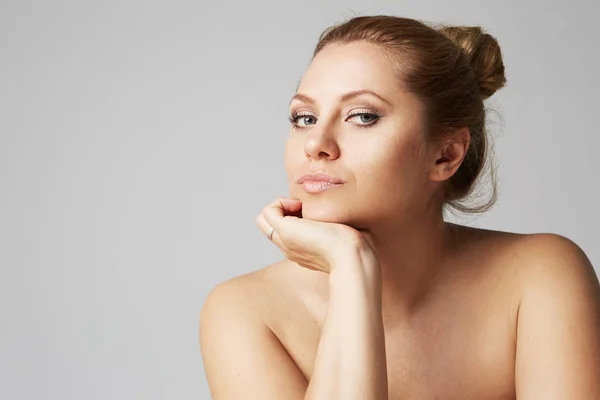 Hermosa chica con ojos grandes y cejas oscuras, con hombros desnudos, mirando a camera.Model con maquillaje desnudo claro, fondo de estudio gris, foto de belleza, espacio de copia, primer plano . — Foto de Stock