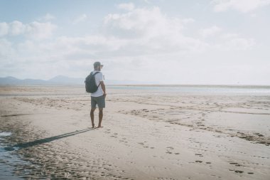 Deniz kıyısında gündoğumu sırt çantası ile ayakta ve ufuk seyir çekici kas sakallı adam.