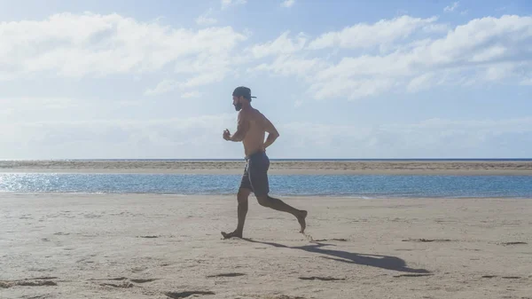 Ajuste joven modelo de fitness deportivo masculino haciendo ejercicio en todo el cuerpo en verano. Guapo fuerte caucásico hombre entrenamiento océano playa . —  Fotos de Stock