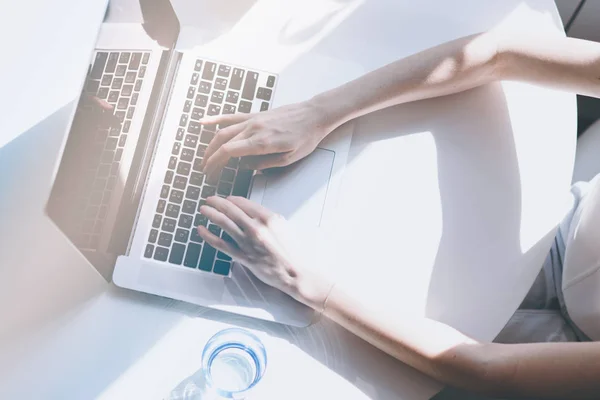 Mooie zakelijke vrouwen hand typen op een laptopcomputer tijdens de vergadering op de houten tafel in licht gekleurd woonkamer van moderne huis. Bovenaanzicht. Zonnige dag. — Stockfoto