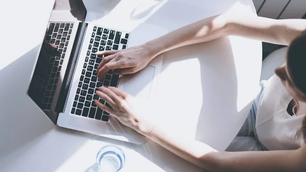 Mooie zakelijke vrouwen hand typen op een laptopcomputer tijdens de vergadering op de houten tafel in licht gekleurd woonkamer van moderne huis. Bovenaanzicht. — Stockfoto