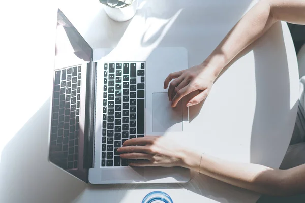 Jonge aantrekkelijke vrouw die werkt op een laptop zitten aan de tafel in de woonkamer van moderne huis. Bovenaanzicht. — Stockfoto