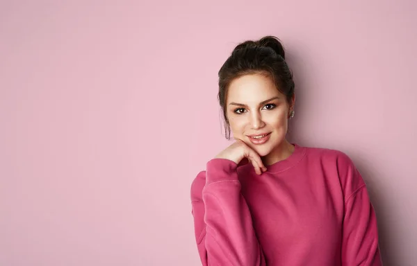 Beautiful young women with big brown eyes wearing pink hoody and looking at camera over empty pink background.Model with light nude make-up, color studio background, copy paste text space. — Stock Photo, Image