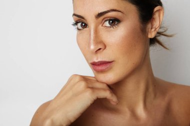 Büyük kahverengi gözleri ve karanlık kaşları kameraya boş beyaz arka plan üzerinde seyir ile güzellik kadın. Işık çıplak makyaj ile model, stüdyo arka planını renklendirin, yapıştırma alanı kopyalayın, yakın çekim.