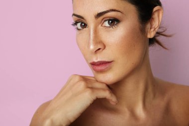 Temiz cilt, doğal makyaj boş pembe renkli arka plan üzerinde olan güzel kadın. Portre kadar kapatın. Moda ve sağlık kozmetik yüz cilt kavramı. Kopya hamur metin alanı.