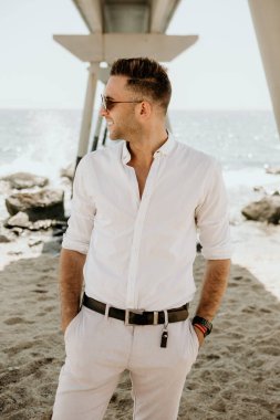 Denizde yürüyen genç yakışıklı adam yaz sezonu keyfini çıkarın. Beyaz genç adam uzakta güneşli gün bakan sakin ol.