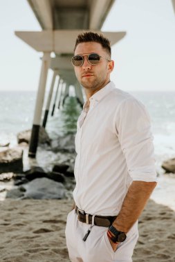 Denizde yürüyen genç yakışıklı adam yaz sezonu keyfini çıkarın. Beyaz genç adam uzakta güneşli gün bakan sakin ol. Dikey.