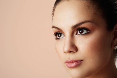 Büyük kahverengi gözleri ve karanlık kaşları uzakta boş renk stüdyo arka plan üzerinde seyir yakışıklı kadın portresi. Işık çıplak makyaj ile model. Yapıştırma alanı ise, yakın çekim. Sağlık cilt kavramı.
