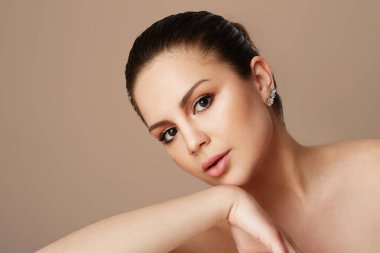 Genç kız büyük kahverengi gözleri ve karanlık kaşları boş renkli stüdyo arka plan üzerinde seyir. Işık çıplak makyaj ile model. Kopya metin alanı yapıştırın, yakın çekim. Sağlık cilt makyaj kavramı.