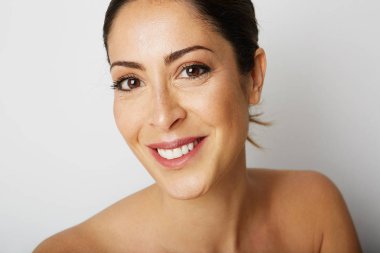 Büyük kahverengi gözleri ve karanlık kaşları uzakta boş beyaz arka plan üzerinde seyir ile mutlu güzellik kadın portresi. Işık çıplak makyaj ile model. Yapıştırma alanı ise, yakın çekim. Sağlık cilt kavramı.