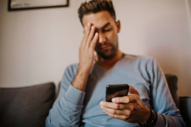 Yakışıklı adam için dalga köpüğü hareket eden smartphone kullanarak web internet ve gönderen sesli mesaj. Adam modern daire Gadget'ı kullanma.